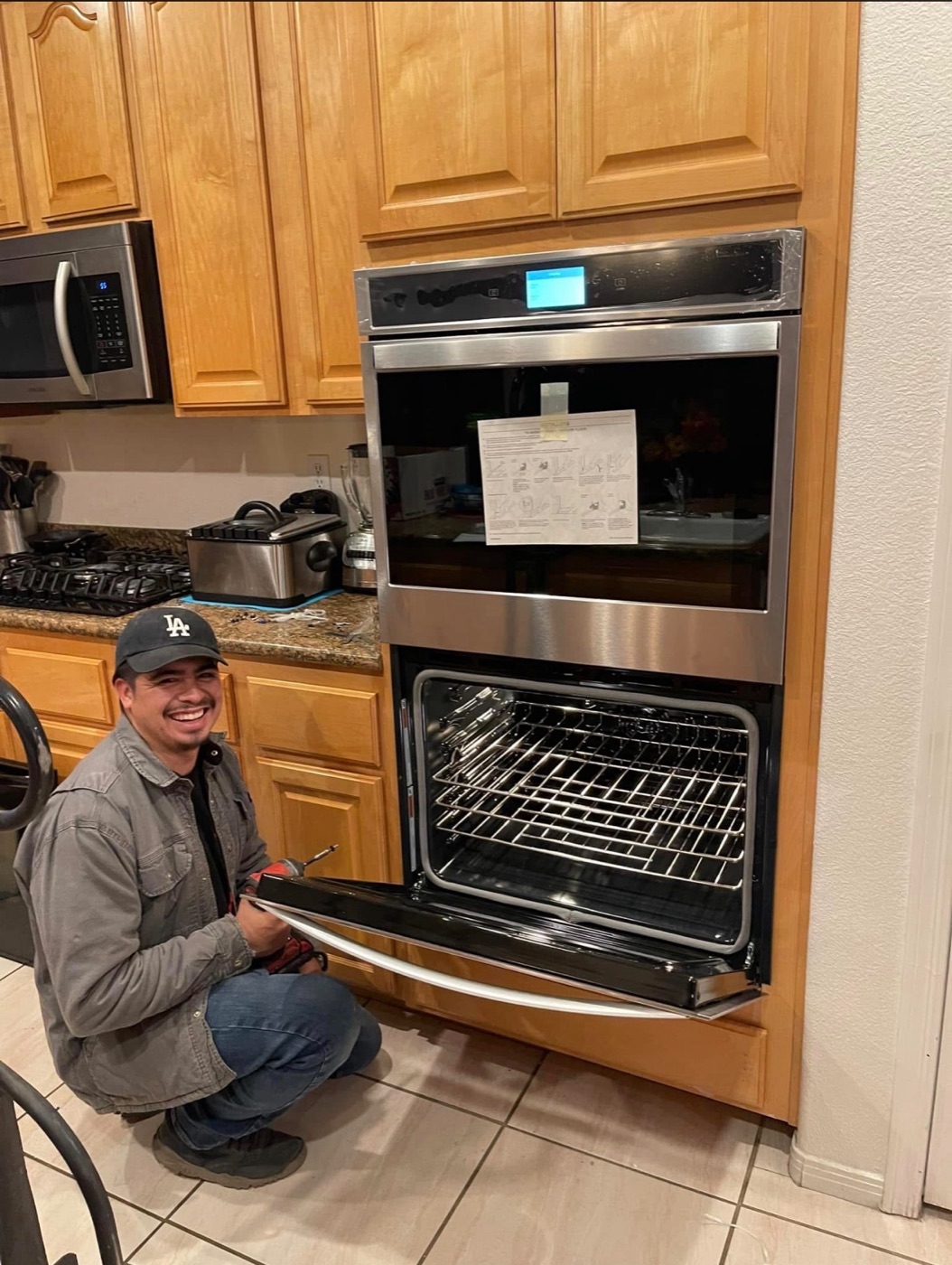 Sergio smiling while finishing installation of a new stainless double wall oven