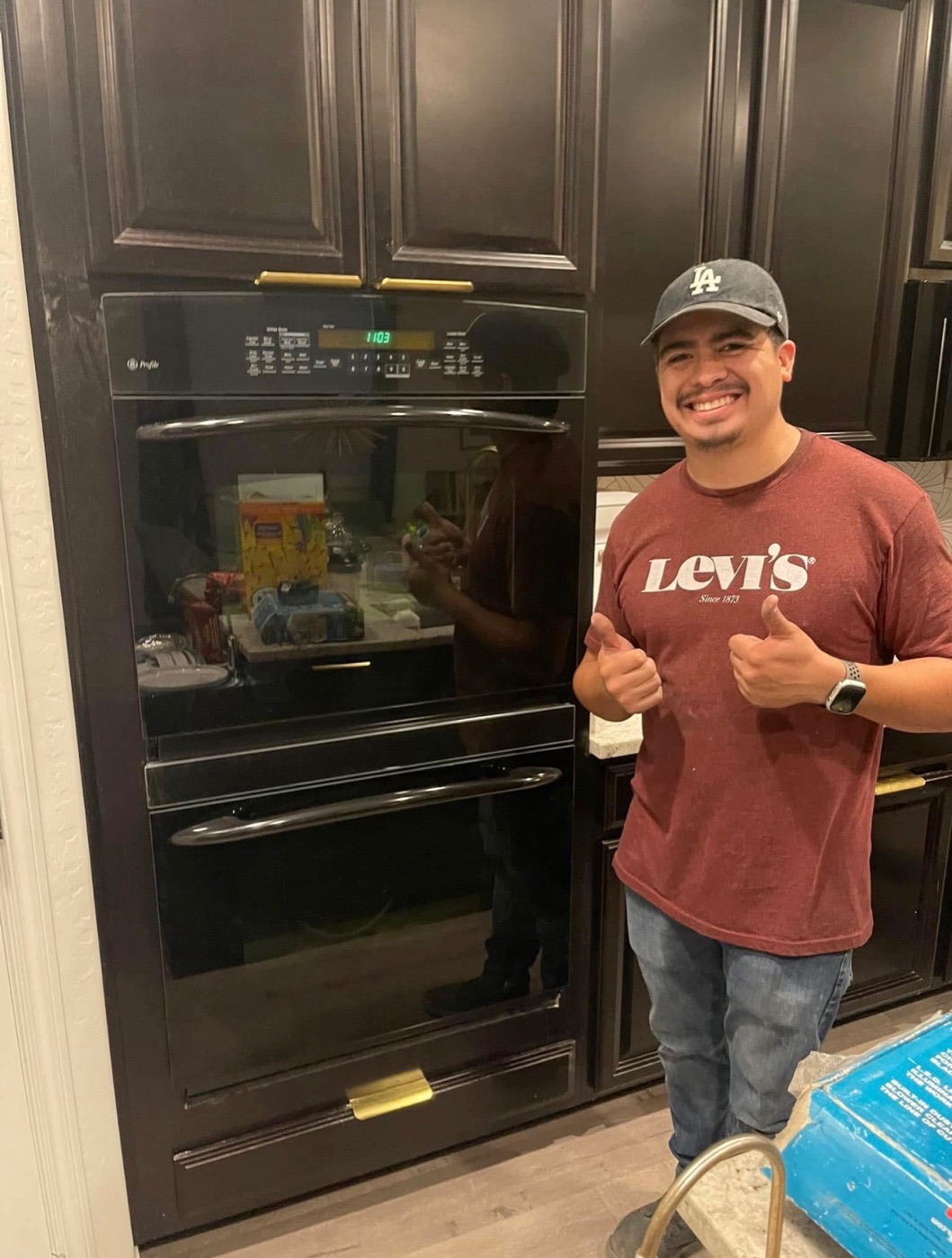 Sergio giving two thumbs up beside a repaired black double wall oven