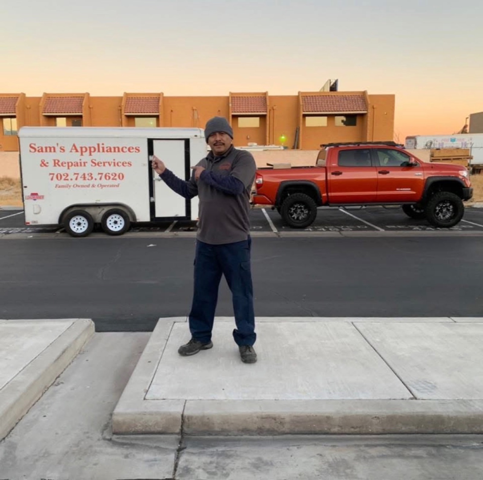 Sam standing in front of the Sam's Appliances trailer and orange Tundra at sunset