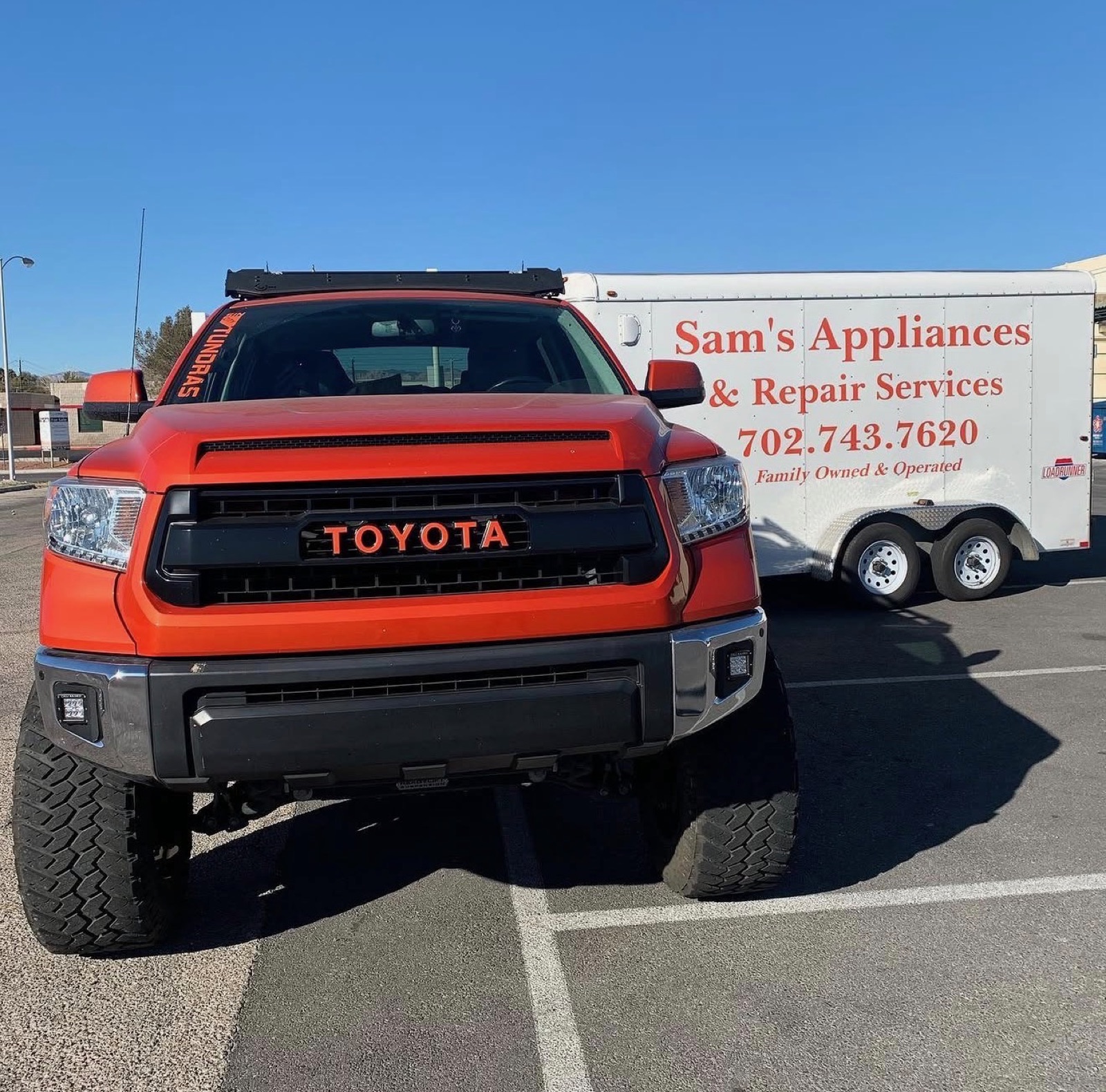 Sam's orange Toyota Tundra parked in front of the white Sam's Appliances & Repair Services trailer